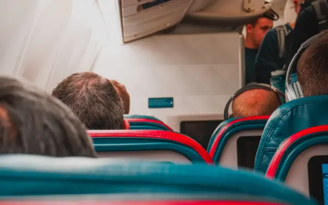 Persona usando el móvil en el asiento de un avión durante el vuelo