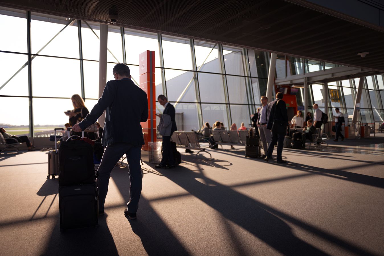 Viajeros con equipaje de mano esperando en una terminal de aeropuerto concurrida