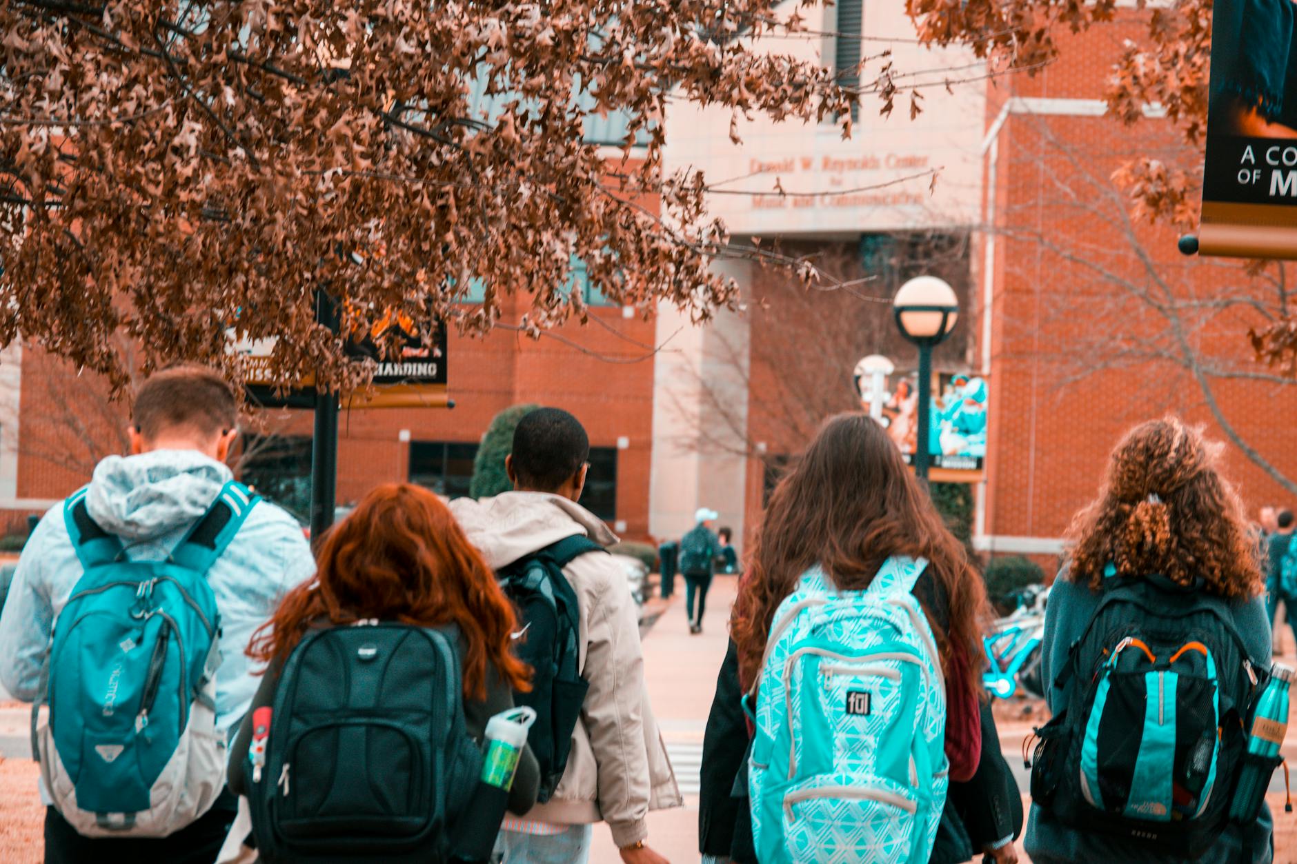 Grupo de estudiantes universitarios con mochilas caminando juntos por el campus