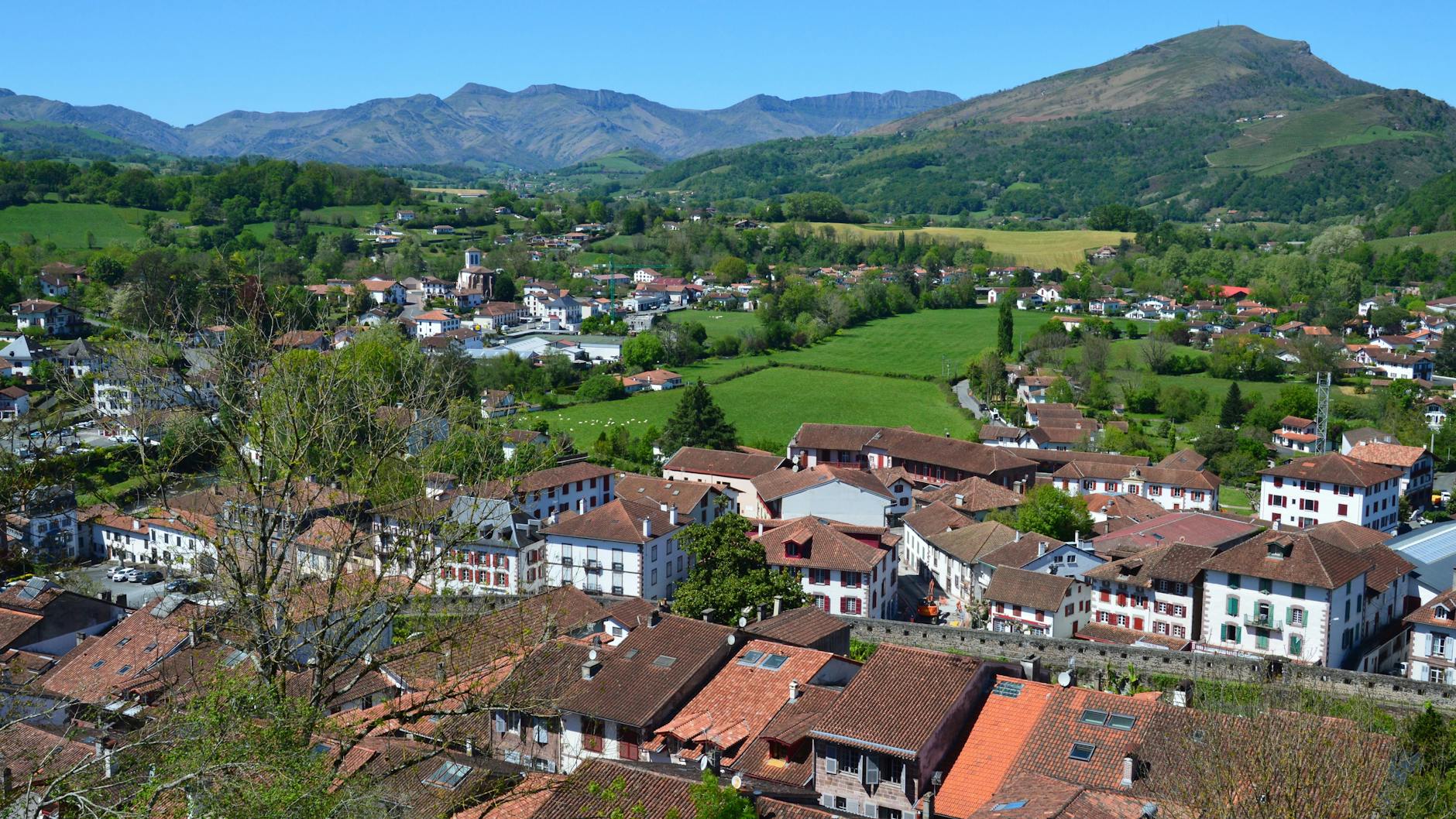 Vista aerea de Saint-Jean-Pied-de-Port con su campiña verde y las montañas pirenaicas al fondo.