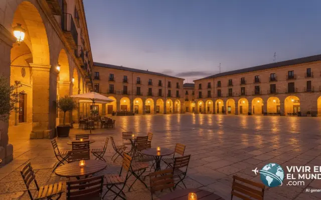 Plaza porticada de un pueblo castellano al anochecer con terraza